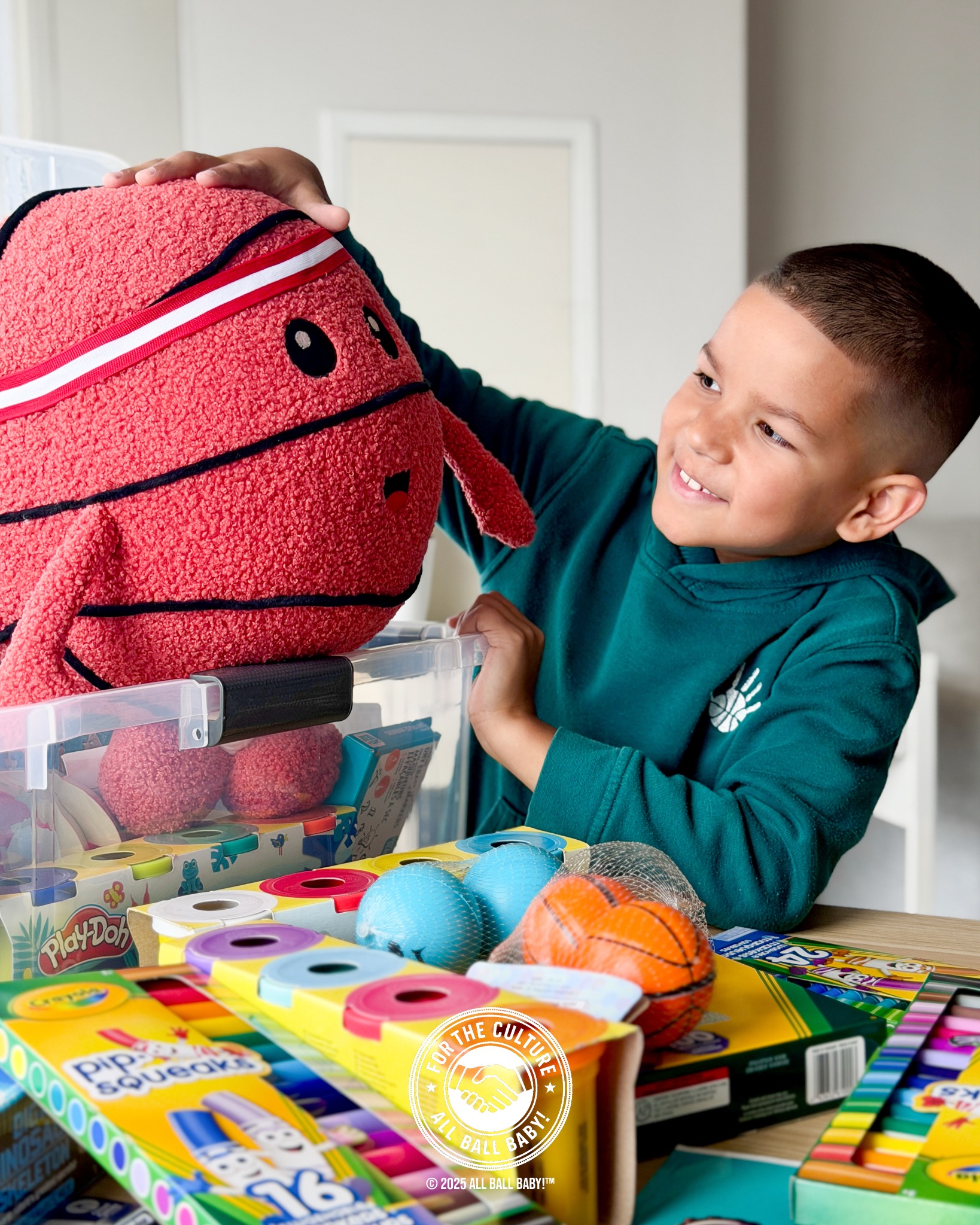 Dre with a basketball plush and donated classroom supplies