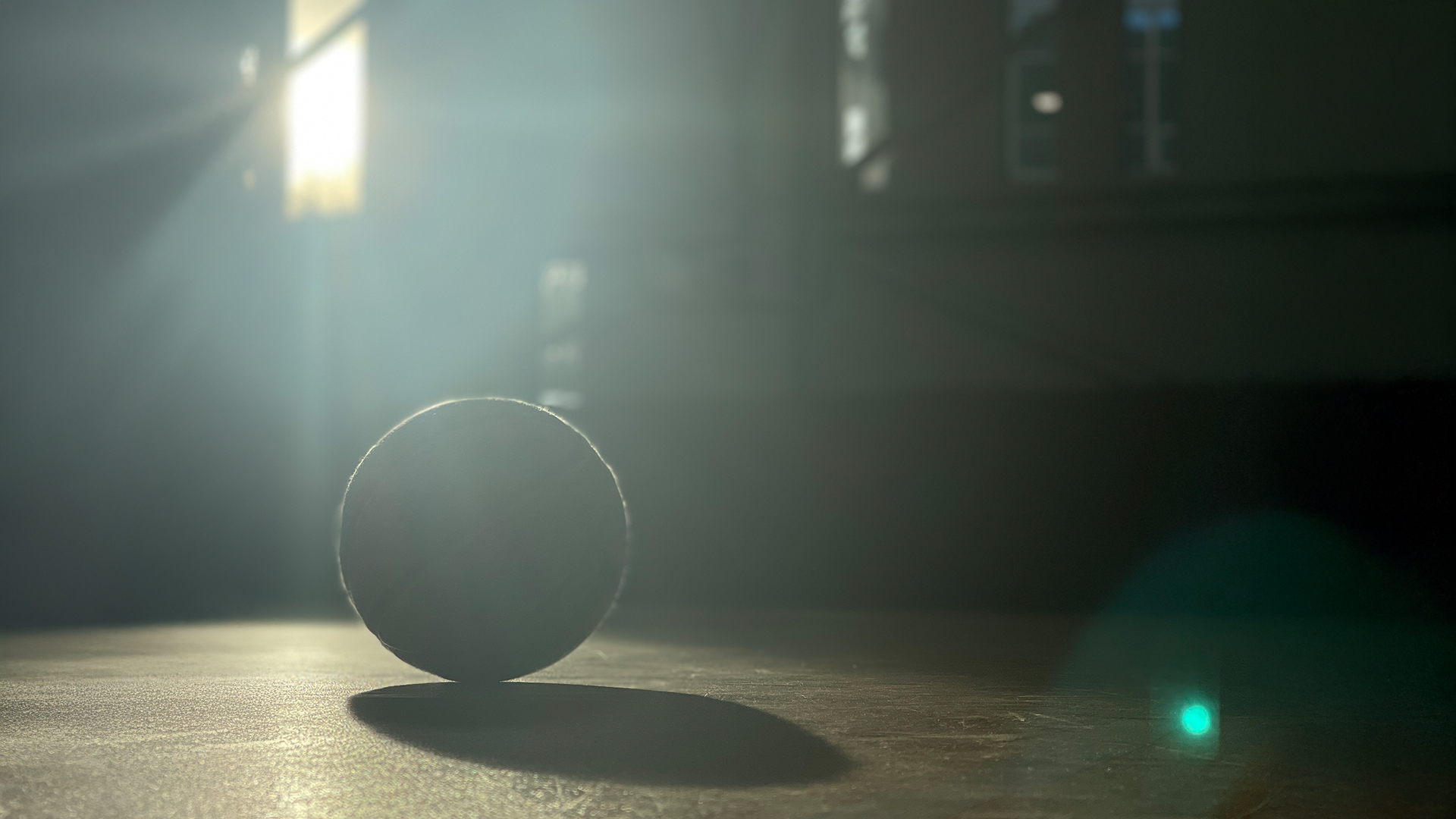 A basketball on a court in a shaft of light